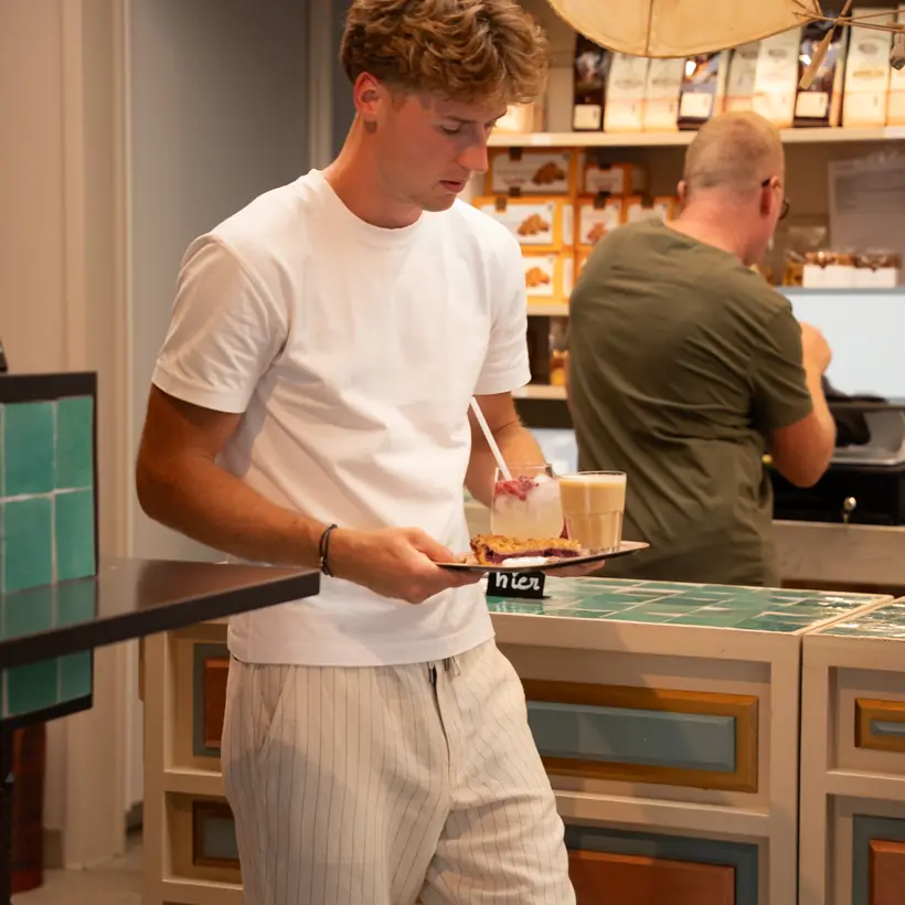 Een dienblad met limonade, koffie en taart wordt naar de tafel gebracht