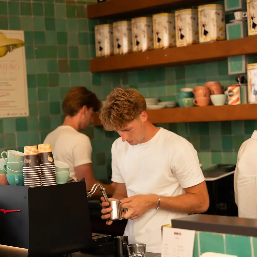 Melk wordt gestoomd aan de espressomachine, voor de groene zellige-tegels