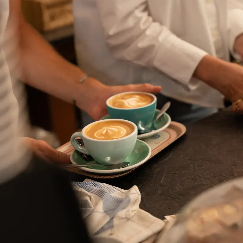 Twee cappuccino's met latte art in mintgroene kopjes op een dienblad
