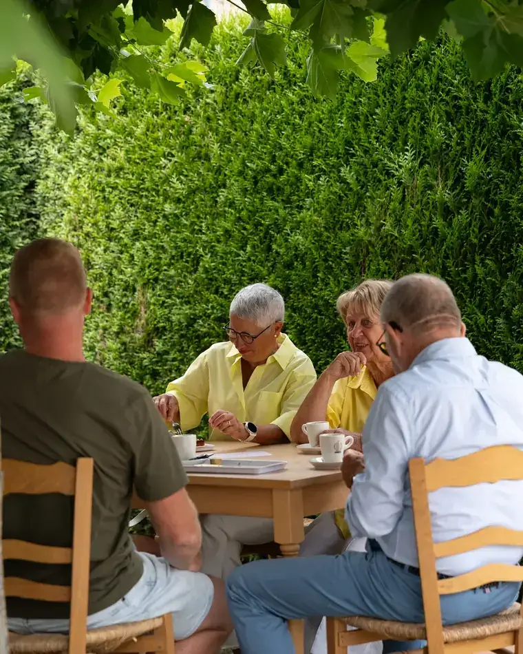 Gasten aan een houten tafel in de tuin naast de branderij